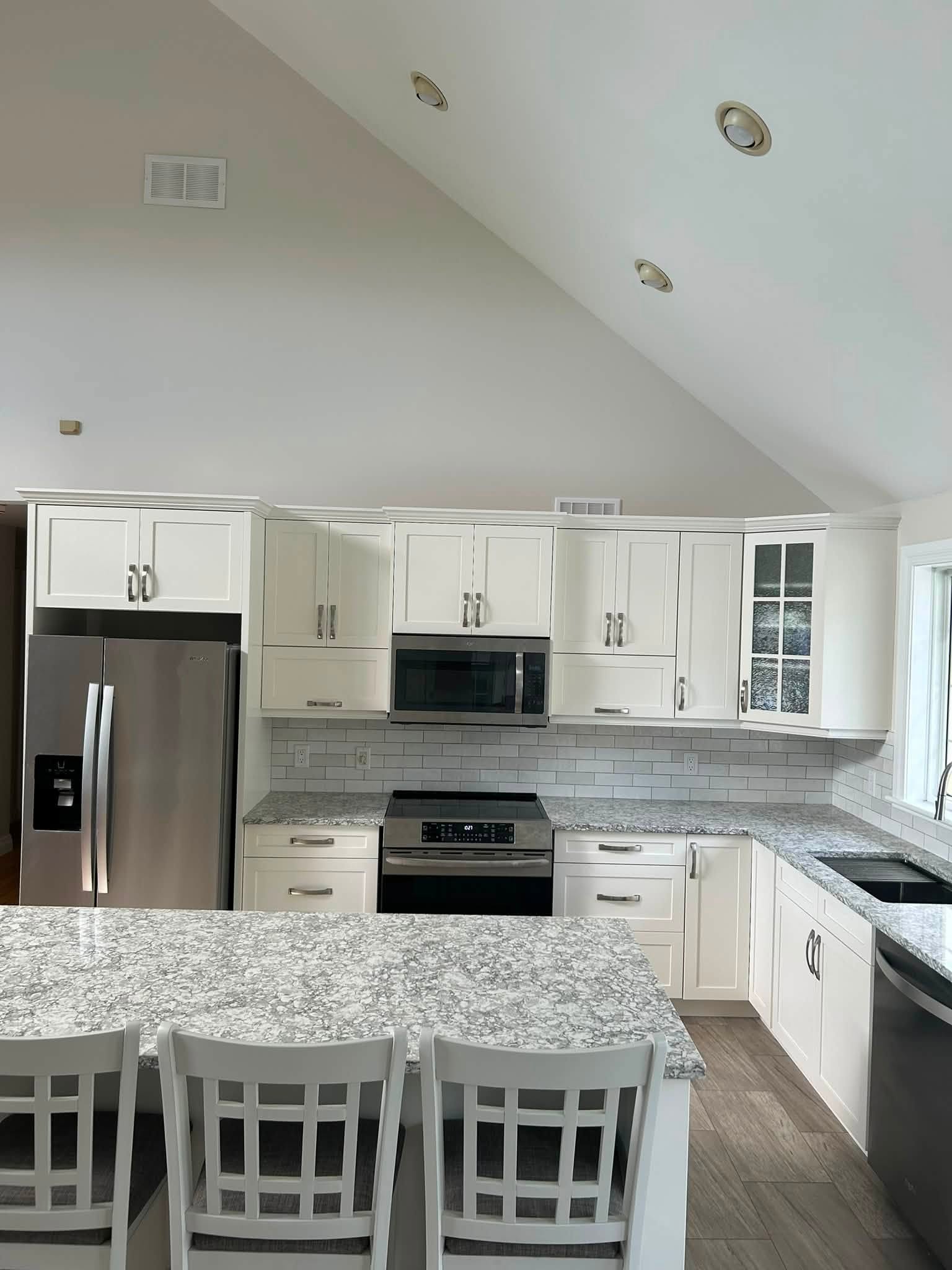 White kitchen cabinetry with a central island and seating.