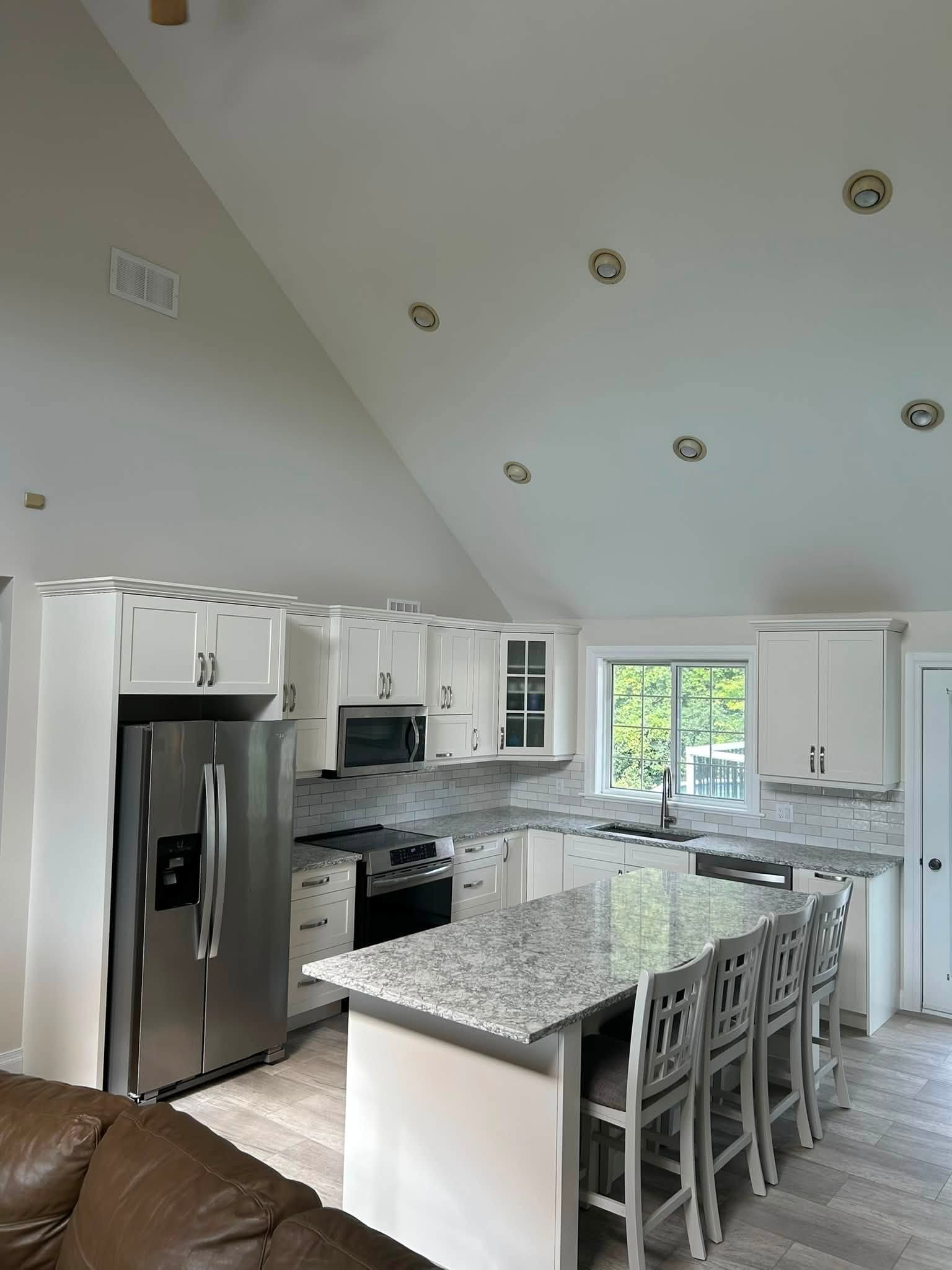 White cabinetry and an island, viewed from the adjoining living space.